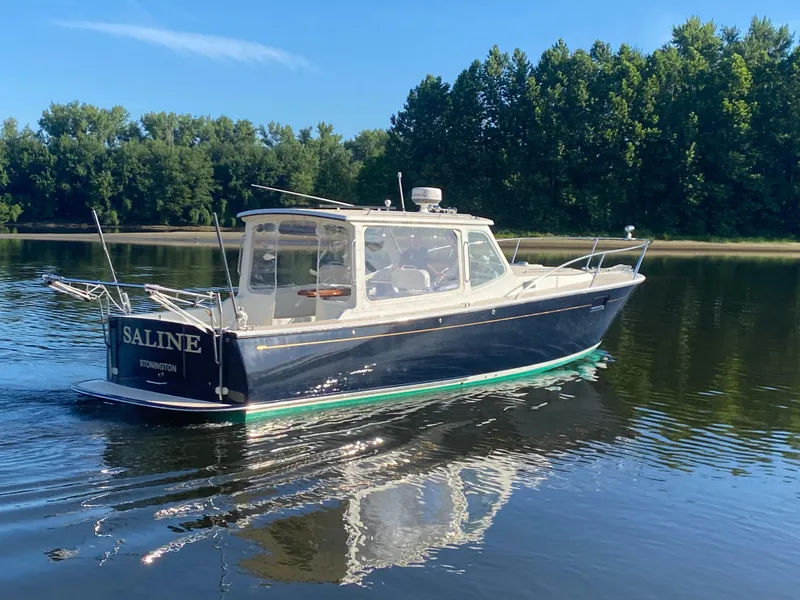 Slide: The Image of 2005 MJM 34z Downeast boat cruising on calm water with lush green trees in the background. - 6