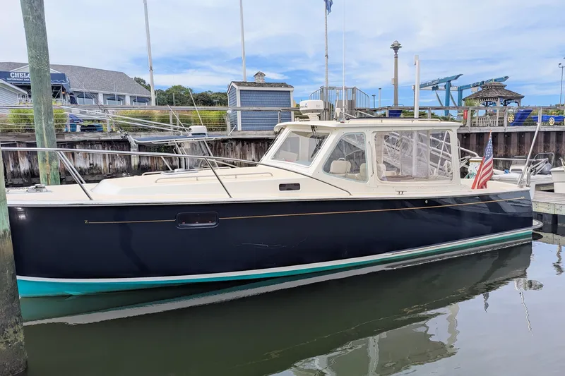 Slide: The Image of 2005 MJM 34z Downeast boat docked in marina, featuring sleek design and American flag. - 7