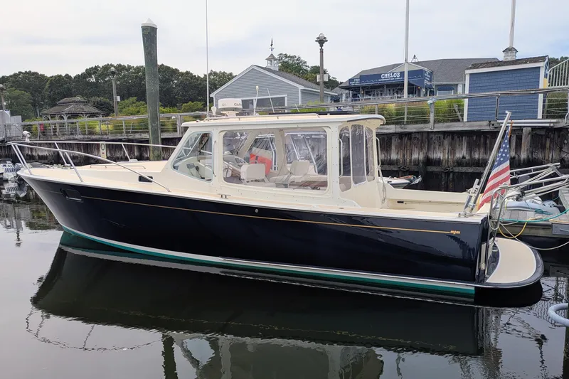 Slide: The Image of 2005 MJM 34z Downeast boat docked in a marina, featuring a sleek design and American flag. - 8