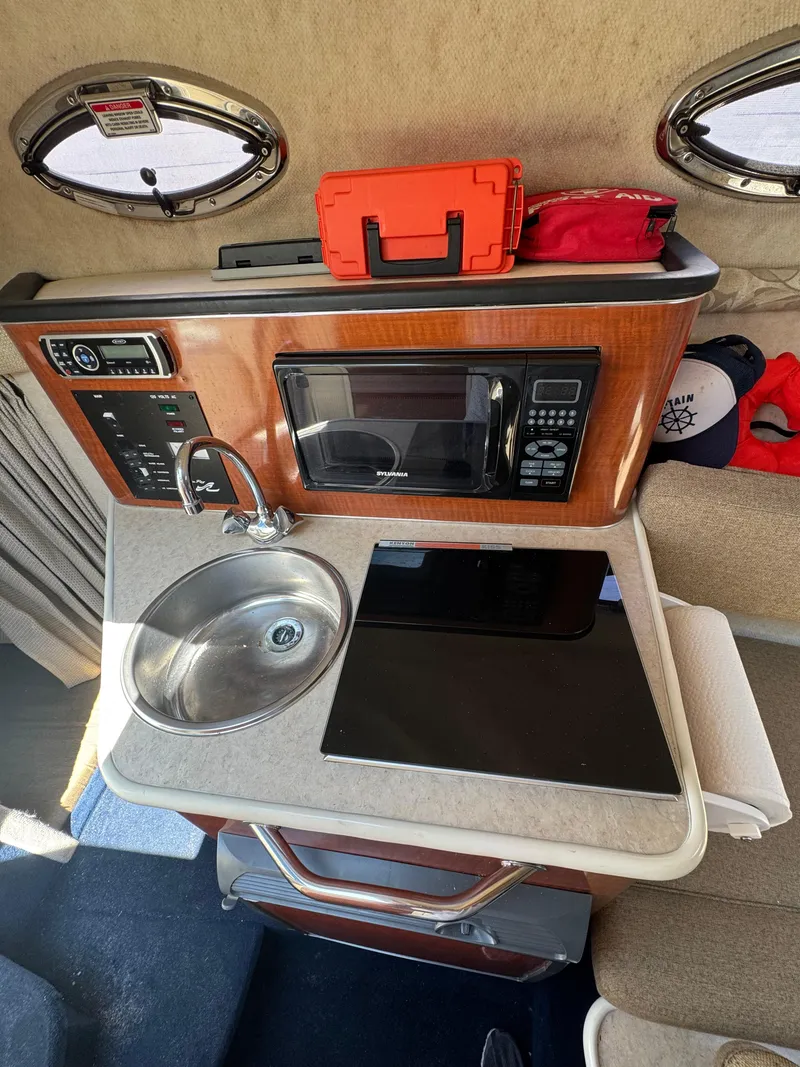Slide: The Image of 2003 Sea Ray 240 Sundancer cabin kitchen with sink, microwave, and storage. - 10