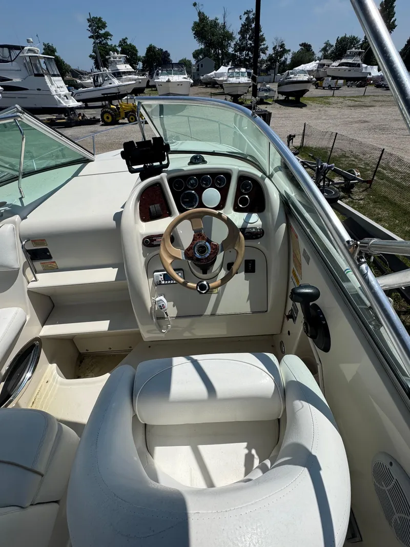 Slide: The Image of 2003 Sea Ray 240 Sundancer helm with steering wheel and control panel, docked in marina. - 6