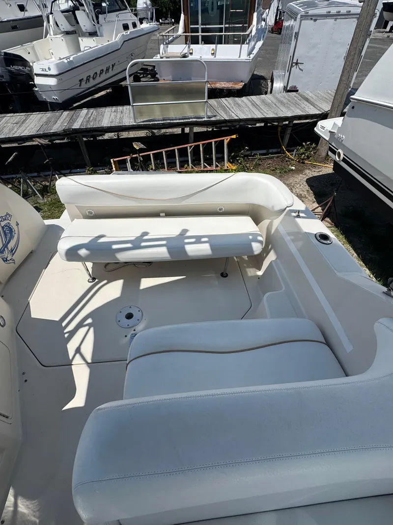 Slide: The Image of 2003 Sea Ray 240 Sundancer boat interior with white seating and docked boats in background. - 8