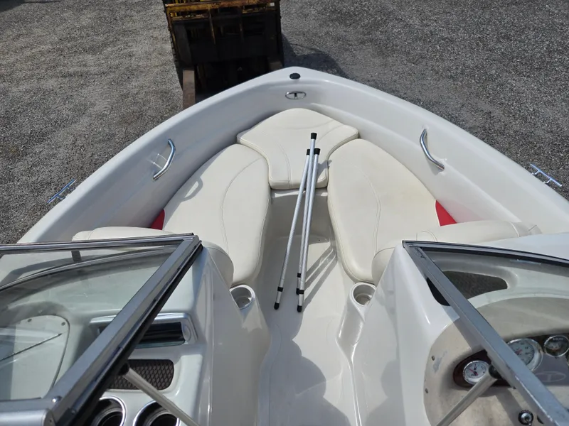 Slide: The Image of 2014 Tahoe Q5i boat interior with white seating and windshield, parked on gravel. - 13