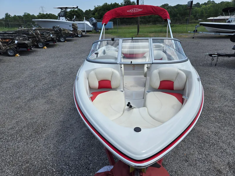 Slide: The Image of 2014 Tahoe Q5i boat with red and white interior, parked on gravel lot. - 3