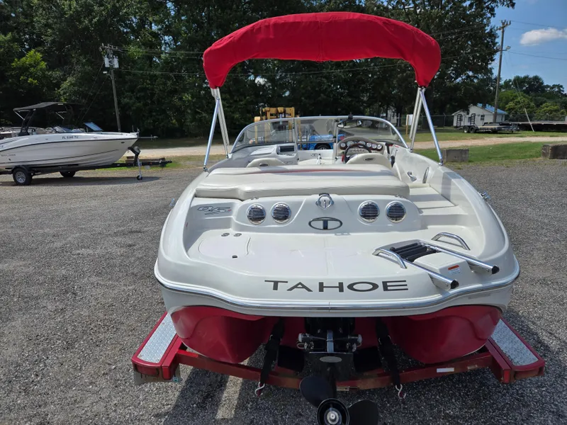 Slide: The Image of 2014 Tahoe Q5i boat with red canopy, parked on a trailer in a lot. - 5