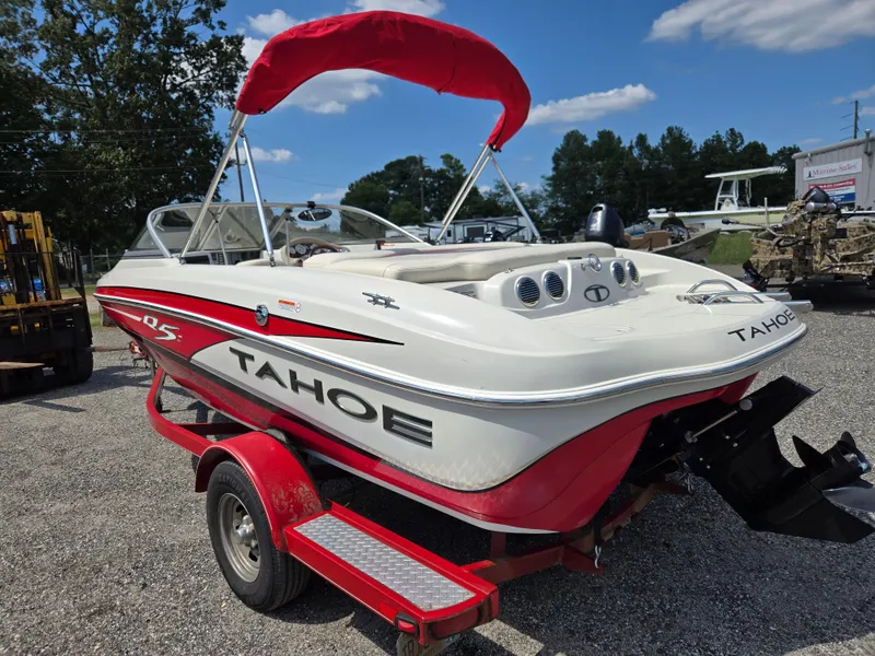 Slide: The Image of 2014 Tahoe Q5i boat with red accents on a trailer, parked outdoors. - 6