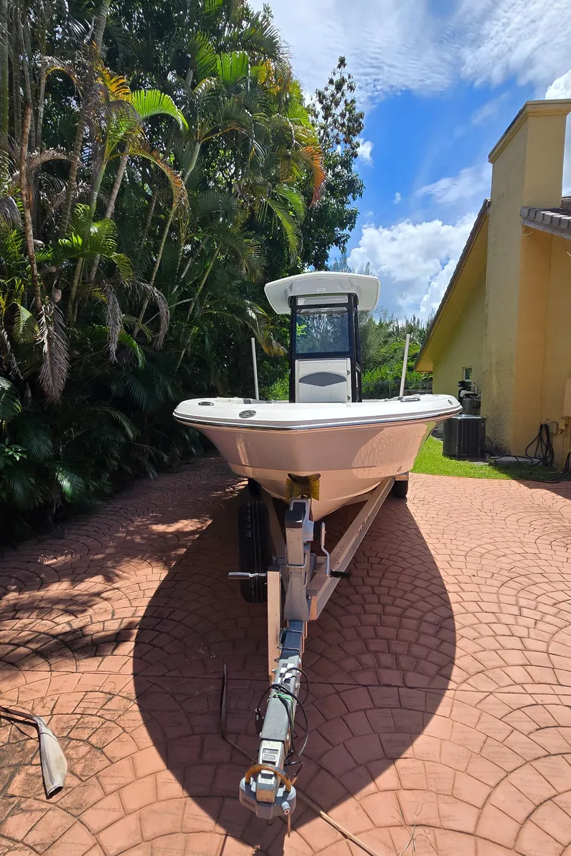 Slide: The Image of 2021 Robalo 246 Cayman boat on trailer, parked on brick driveway, surrounded by lush greenery. - 6