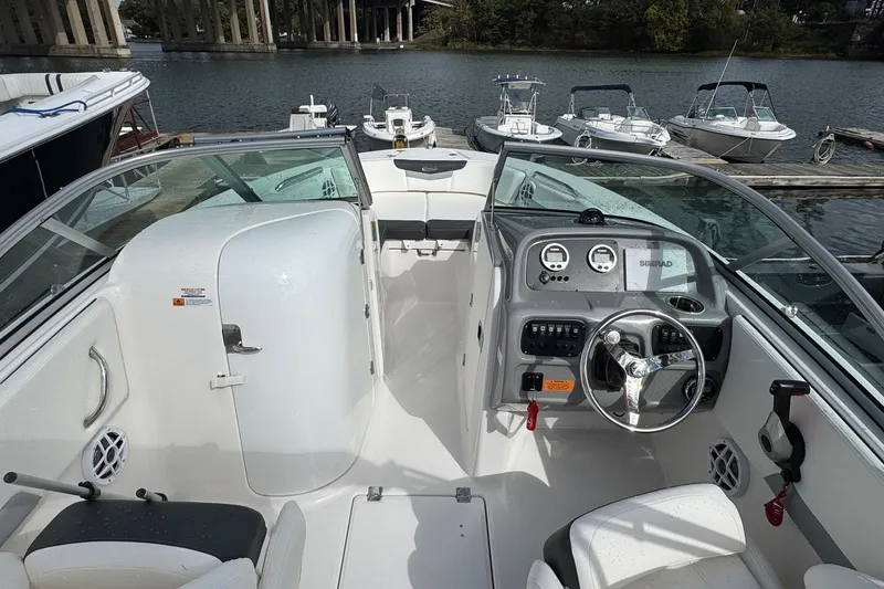 Slide: The Image of 2024 Robalo R207 Dual Console boat interior with steering wheel and dashboard, docked by the water. - 25