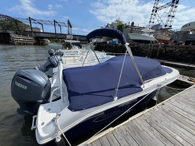 Slide: The Image of 2024 Robalo R207 Dual Console boat docked, covered with blue tarp, Yamaha engine visible. - 3