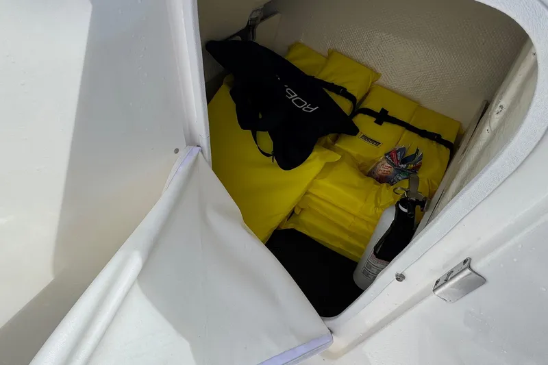 Slide: The Image of Storage compartment in 2024 Robalo R207 Dual Console with safety gear and fire extinguisher. - 31