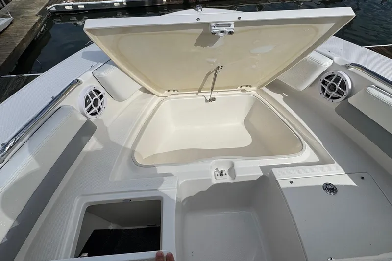 Slide: The Image of 2024 Robalo R207 Dual Console boat with open storage compartment and speakers. - 36
