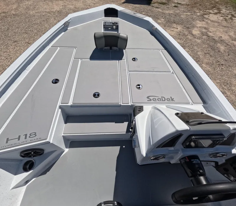 Slide: The Image of 2026 Xpress H 18 Bass boat deck with SeaDek flooring, steering console, and seating. - 2