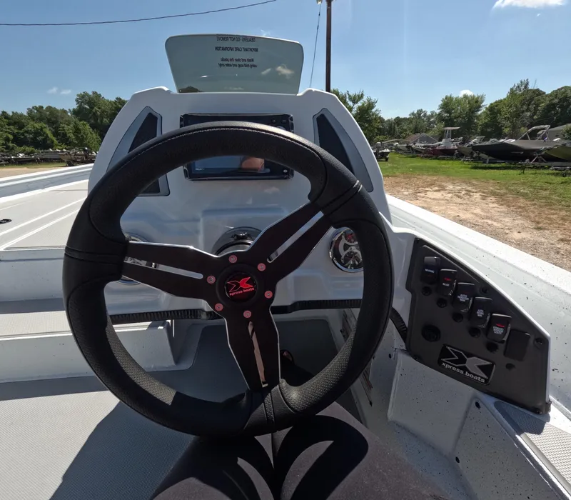 Slide: The Image of Steering wheel of 2026 Xpress H 18 BASS boat, showcasing dashboard controls and outdoor setting. - 5