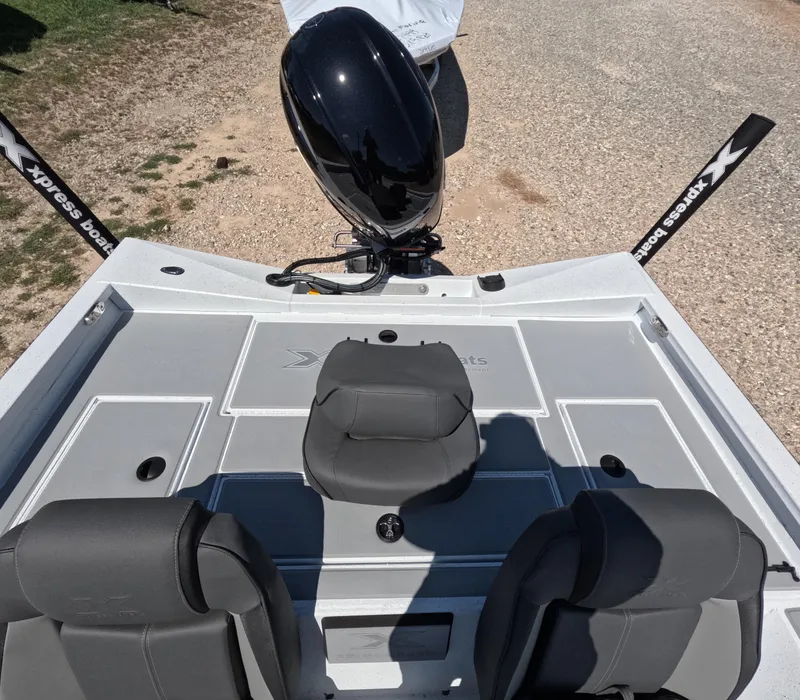 Slide: The Image of 2026 Xpress H 18 BASS boat interior with seats and motor, parked on gravel. - 7
