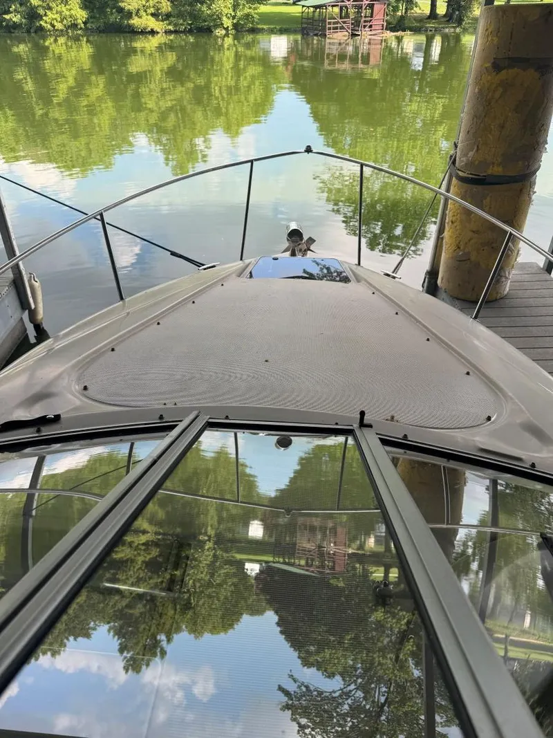 Slide: The Image of Bow view of a 2000 Regal Commodore 2460 boat docked on a serene lake. - 13