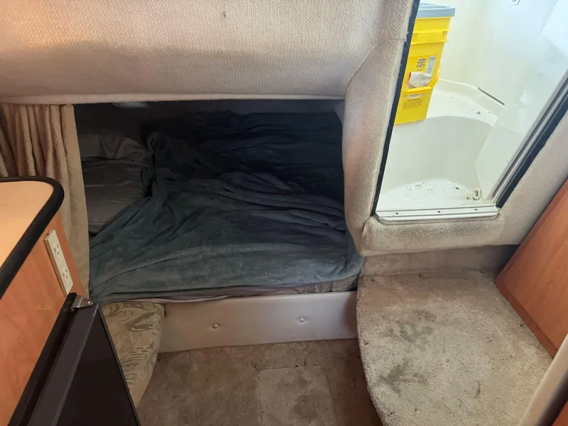Slide: The Image of Interior cabin of a 2000 Regal Commodore 2460 boat with bed and storage area. - 18