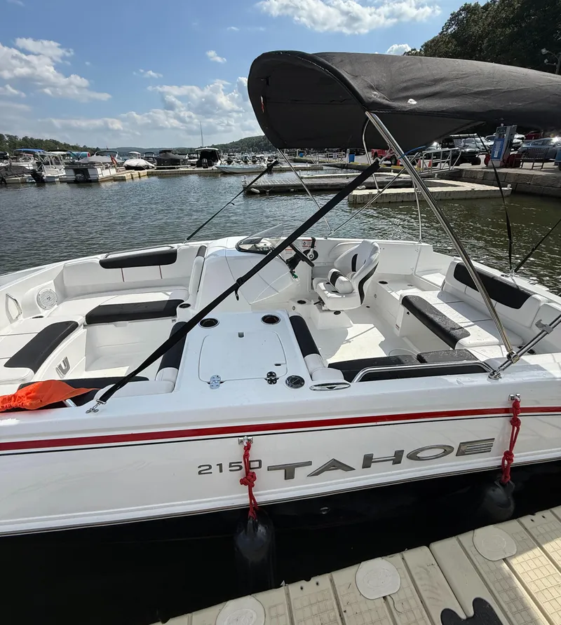 Slide: The Image of 2023 Tahoe 2150 boat docked at marina, featuring spacious seating and canopy. - 6