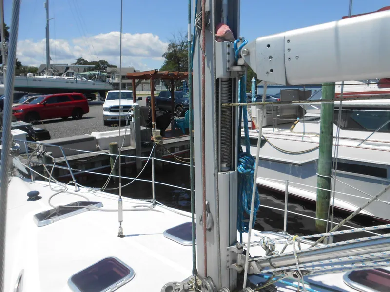 Slide: The Image of 2004 Catalina 387 sailboat docked at marina with visible rigging and nearby parked cars. - 36