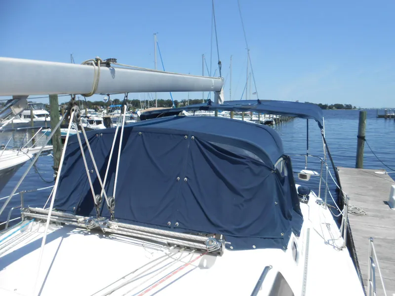 Slide: The Image of 2004 Catalina 387 sailboat docked, featuring blue canvas covers and rigging, under clear skies. - 39
