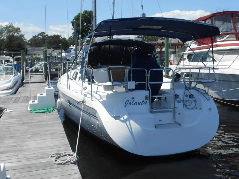 Slide: The Image of 2004 Catalina 387 sailboat docked at marina, featuring blue canopy and white hull. - 40