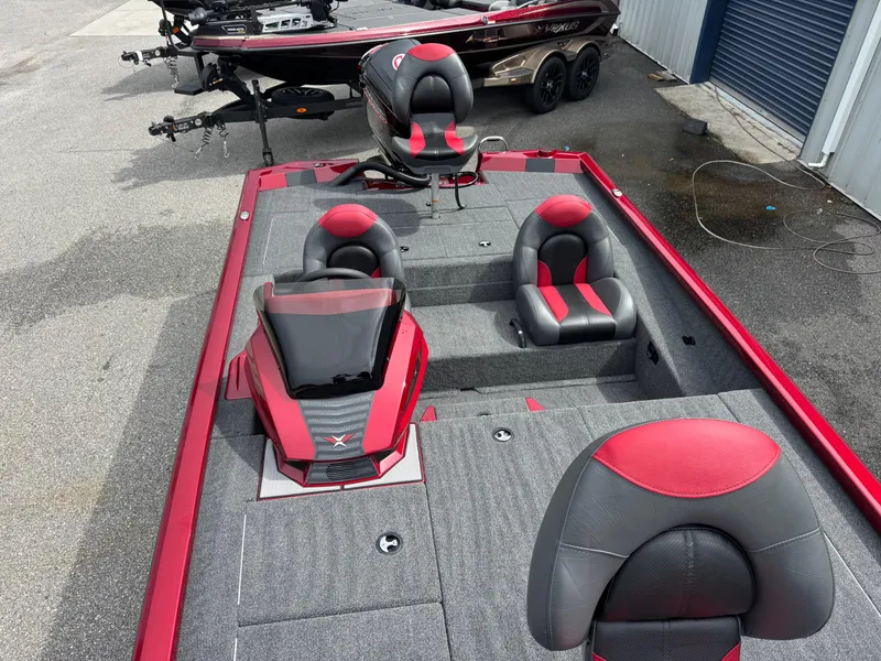 Slide: The Image of 2026 Vexus AVX1880 boat with red and gray seating, parked outdoors. - 10