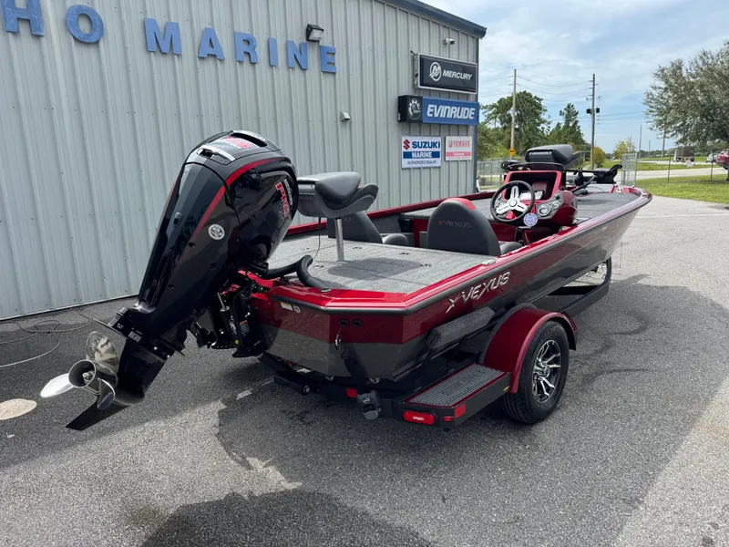 Slide: The Image of 2026 Vexus AVX1880 boat with outboard motor, parked outside a marine dealership. - 21