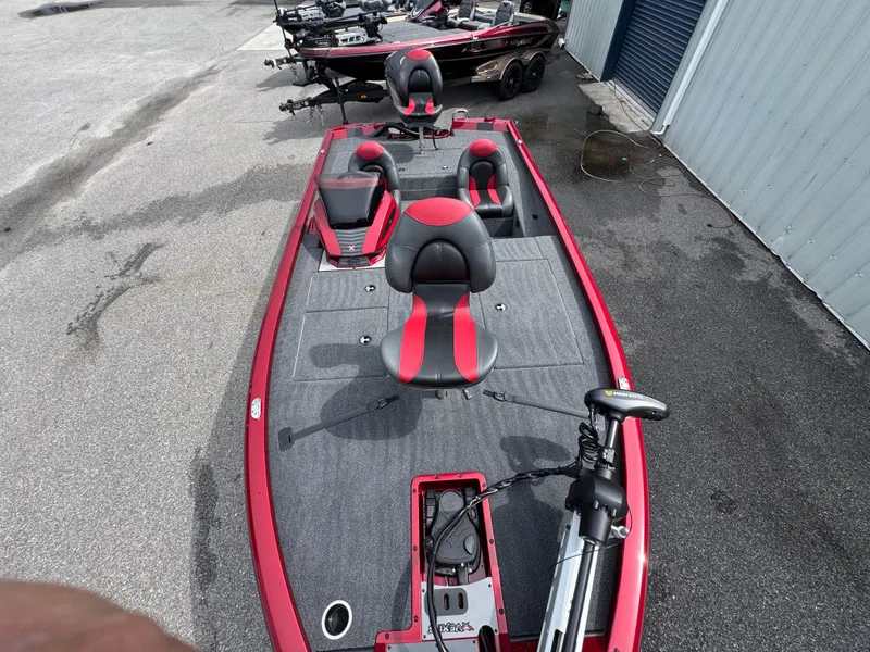 Slide: The Image of 2026 Vexus AVX1880 boat with red and gray seating, parked outdoors. - 9