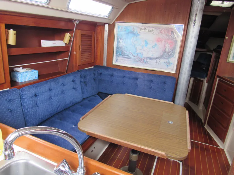 Slide: The Image of Interior of 1986 Catalina 36 sailboat with blue seating and wooden table. - 10