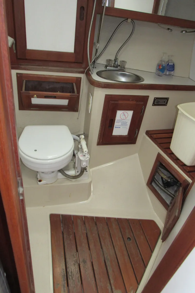 Slide: The Image of 1986 Catalina 36 boat bathroom with toilet, sink, and wooden accents. - 13