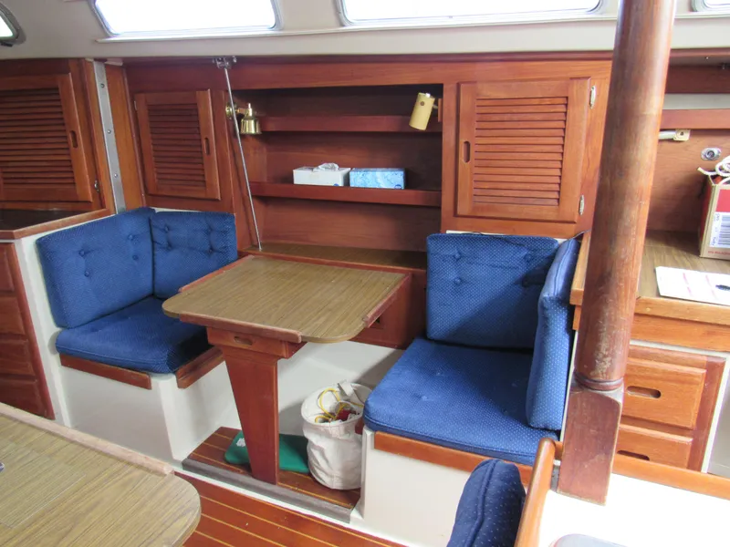 Slide: The Image of Interior of 1986 Catalina 36 sailboat with wooden table and blue cushioned seating. - 9