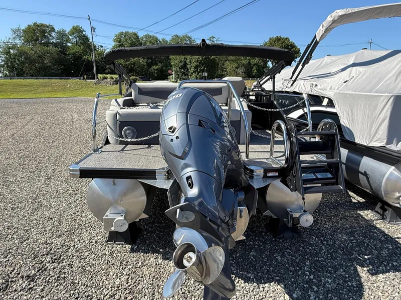 Slide: The Image of 2025 Barletta C22UC pontoon boat with outboard motor, parked on gravel. - 17