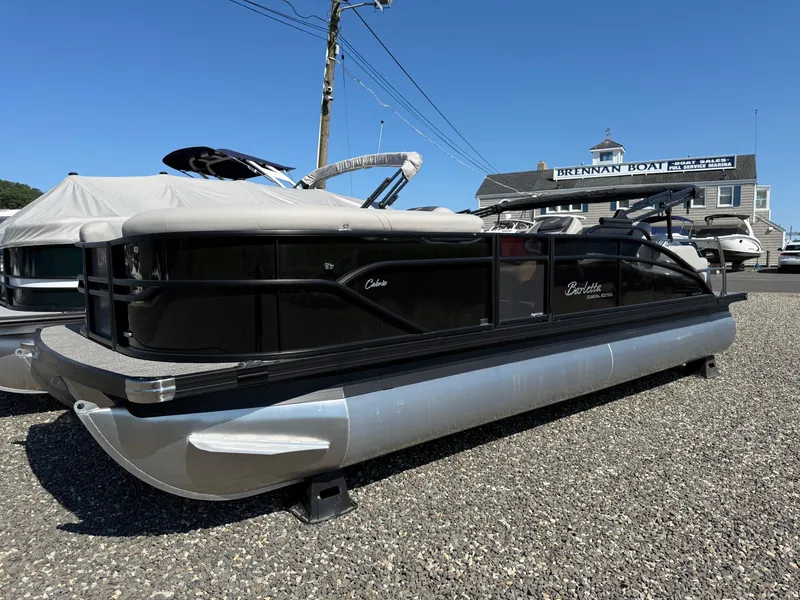 Slide: The Image of 2025 Barletta C22UC pontoon boat displayed at a marina under clear blue skies. - 2