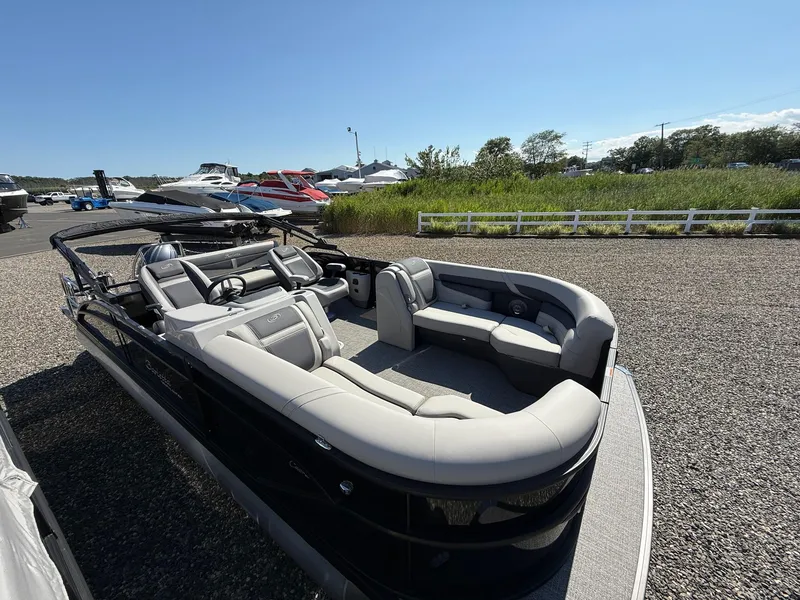 Slide: The Image of 2025 Barletta C22UC pontoon boat with luxurious seating, parked outdoors on gravel. - 5