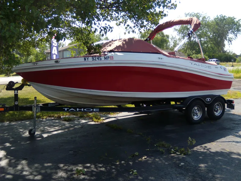 The Image of 2018 Tahoe 500 TS boat on trailer, red and white, parked under a tree. - 0