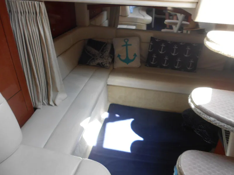 Slide: The Image of Interior of 2005 Sea Ray 340 Sundancer with nautical-themed cushions and cozy seating area. - 11