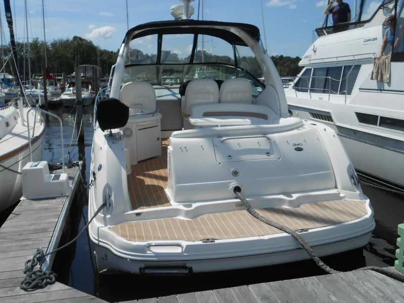 Slide: The Image of 2005 Sea Ray 340 Sundancer docked at marina, showcasing spacious deck and seating area. - 2
