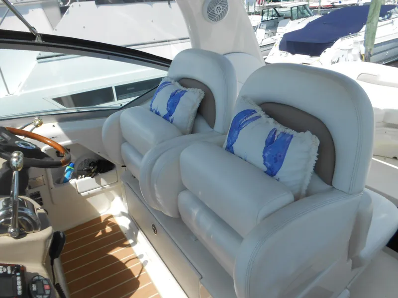 Slide: The Image of 2005 Sea Ray 340 Sundancer cockpit with plush seating and nautical-themed cushions. - 25