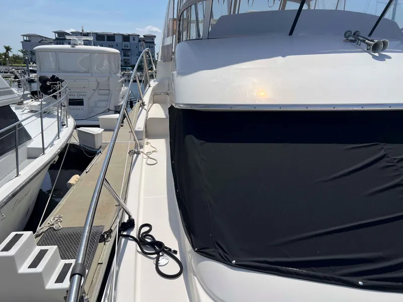 Slide: The Image of 2005 Silverton 38 Sport Bridge yacht docked at marina, side view with covered windshield. - 13
