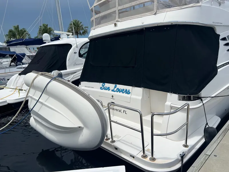 Slide: The Image of 2005 Silverton 38 Sport Bridge yacht docked, featuring black covers and a mounted dinghy. - 2