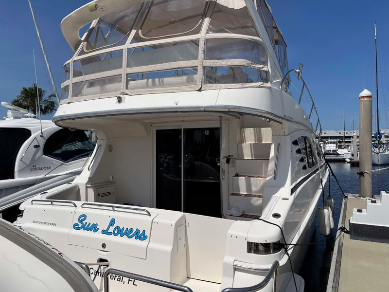 Slide: The Image of 2005 Silverton 38 Sport Bridge yacht docked, featuring "Sun Lovers" name, sunny marina setting. - 4