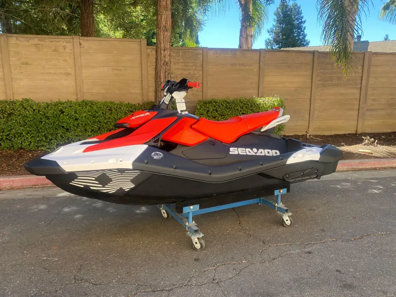 Slide: The Image of 2025 Sea-Doo SPARK TRIXX 3up jet ski with red and black design on a stand. - 0