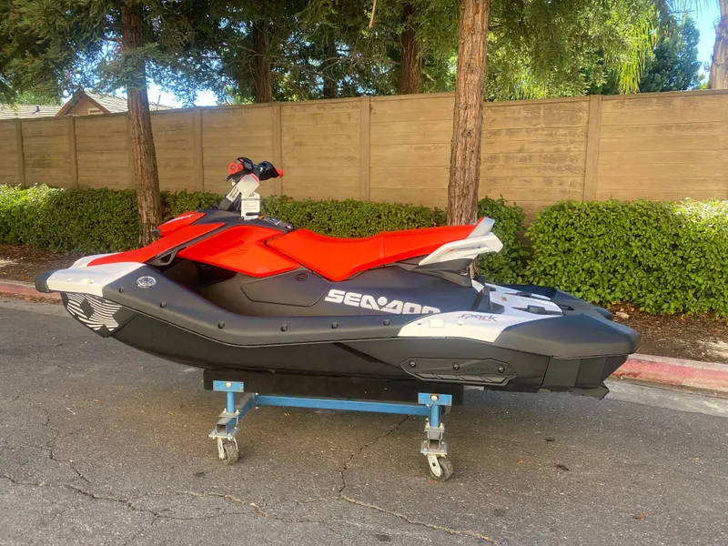 Slide: The Image of 2025 Sea-Doo SPARK TRIXX 3up jet ski on a wheeled stand, outdoors. - 1