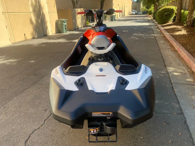 Slide: The Image of 2025 Sea-Doo SPARK TRIXX 3up jet ski parked on a sunny street. - 3