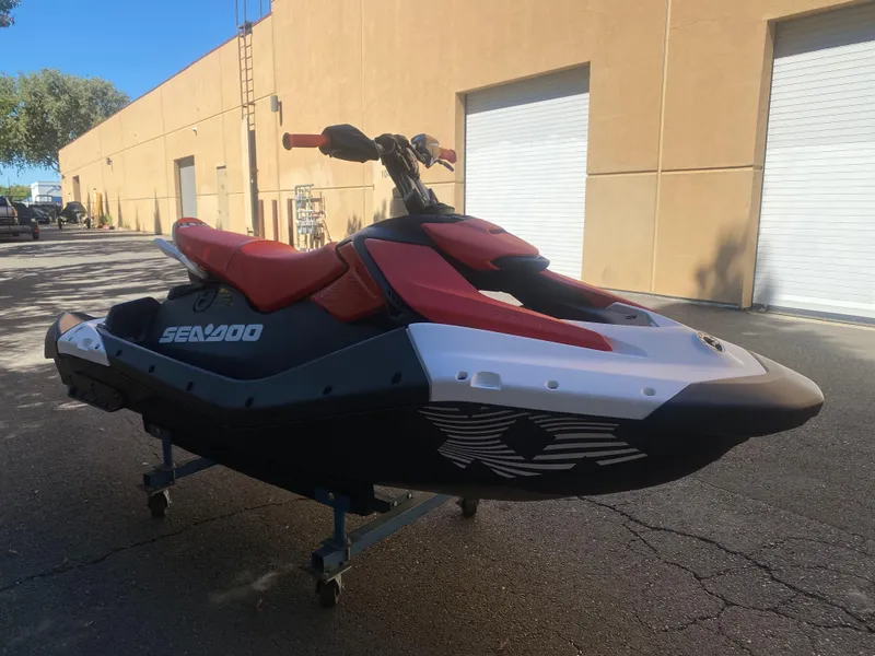 Slide: The Image of 2025 Sea-Doo SPARK TRIXX 3up jet ski parked outdoors, featuring red and black design. - 5