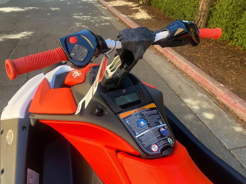 Slide: The Image of 2025 Sea-Doo SPARK TRIXX 3up handlebars and controls, featuring vibrant orange accents. - 7