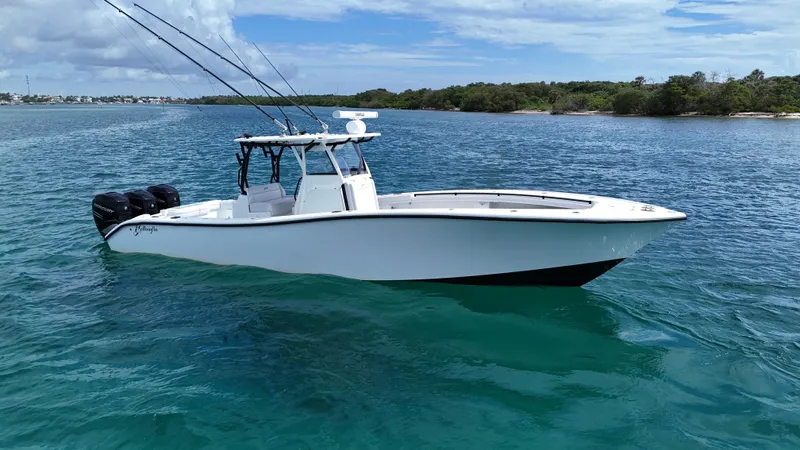 Slide: The Image of 2017 Yellowfin 36 Offshore boat on clear blue water, with fishing rods and triple engines. - 0