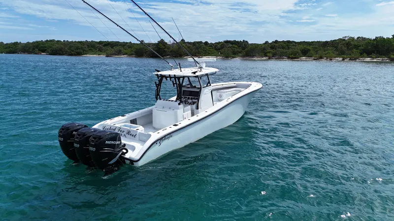 Slide: The Image of 2017 Yellowfin 36 Offshore boat on clear blue water near a forested shoreline. - 4