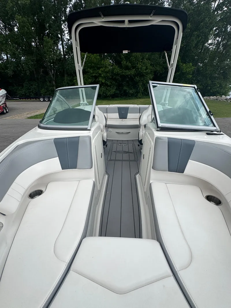 Slide: The Image of 2021 Chaparral 19 SSI Sport boat interior with seating and windshield, parked outdoors. - 12