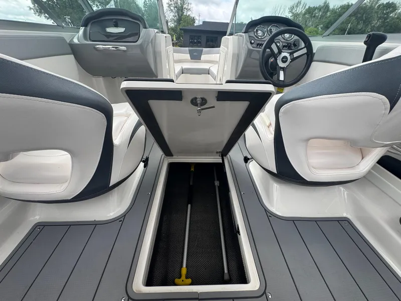 Slide: The Image of 2021 Chaparral 19 SSI Sport boat interior with open storage compartment and steering wheel. - 19