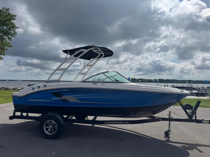 Slide: The Image of 2021 Chaparral 19 SSI Sport boat on trailer by a lake under cloudy sky. - 3